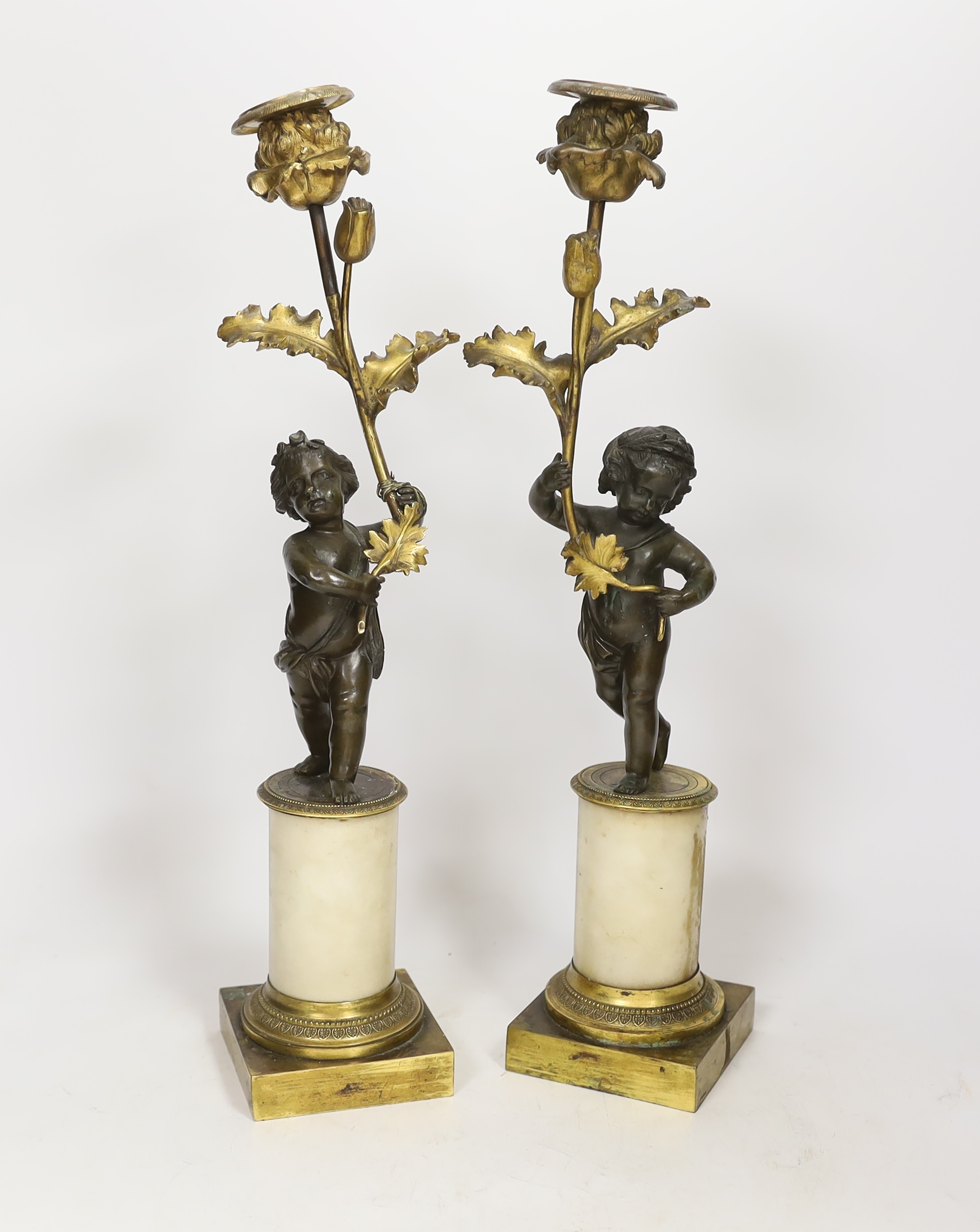 A pair of Regency bronze and ormolu amorini candlesticks, with white marble plinths, 40cm. Condition - fair